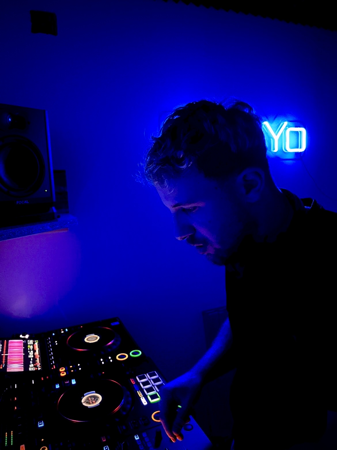 Alcer aux platines dans son studio éclairé en bleu